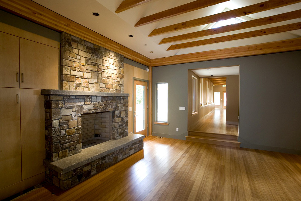Ejemplo de salón abierto actual de tamaño medio con suelo de bambú, todas las chimeneas, marco de chimenea de piedra y pared multimedia