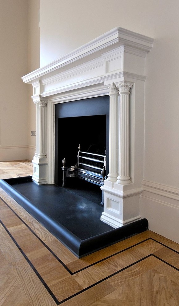 ロンドンにある高級な広いトラディショナルスタイルのおしゃれなリビング (白い壁、無垢フローリング、標準型暖炉、漆喰の暖炉まわり、茶色い床) の写真