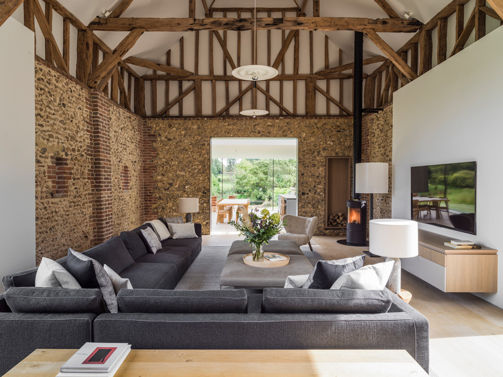 This is an example of a contemporary open plan living room in London with white walls, light hardwood flooring, a wall mounted tv, beige floors, exposed beams and a vaulted ceiling.