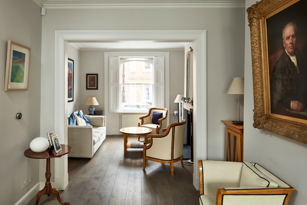 Klassisches Wohnzimmer mit dunklem Holzboden, Kamin, Kaminumrandung aus Stein und grauer Wandfarbe in London