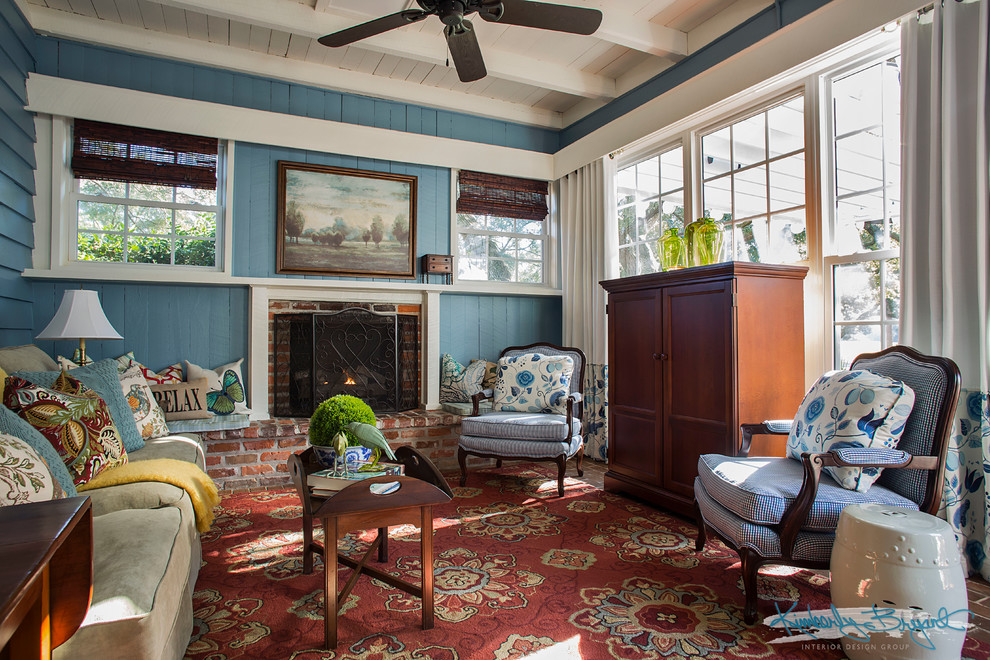 Cette image montre un salon rustique de taille moyenne et ouvert avec un mur bleu, un sol en bois brun, une cheminée standard, un manteau de cheminée en brique et un téléviseur dissimulé.