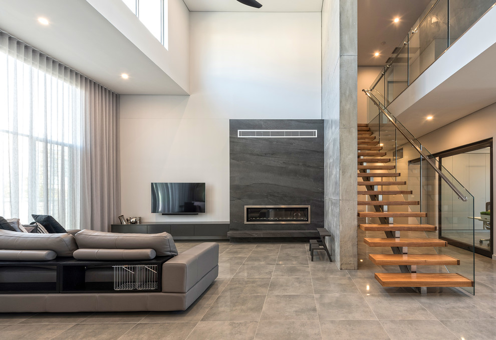 Modelo de salón para visitas abierto contemporáneo con paredes blancas, suelo de cemento, chimenea lineal, televisor colgado en la pared y suelo gris