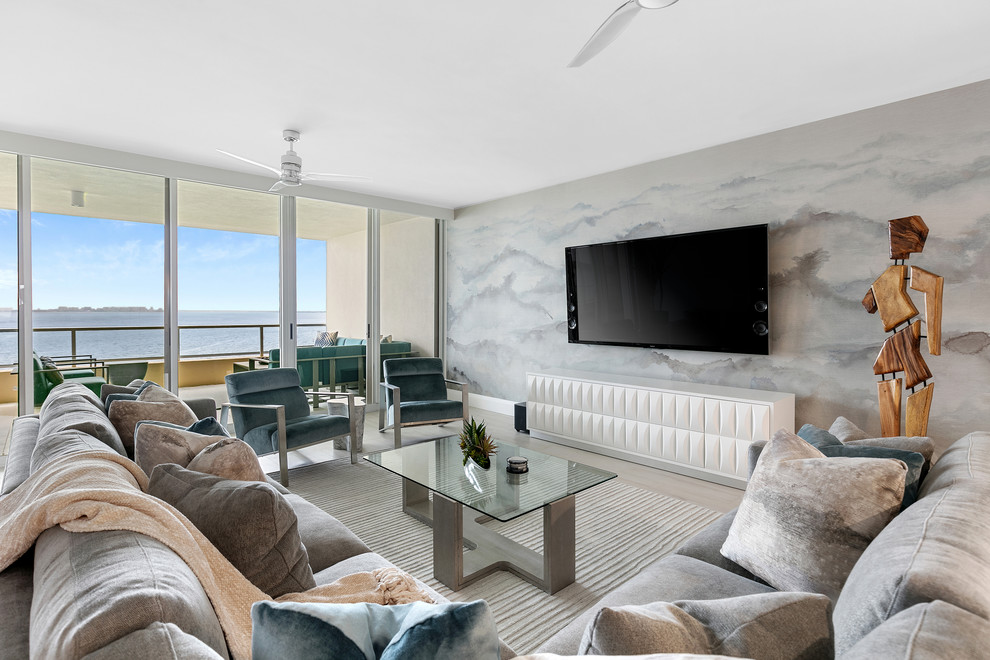 Contemporary open plan living room feature wall in Tampa with grey walls, light hardwood flooring, a wall mounted tv and grey floors.