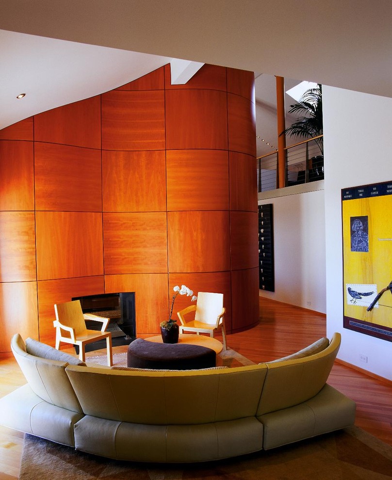 Пример оригинального дизайна: парадная, открытая гостиная комната с белыми стенами, паркетным полом среднего тона, двусторонним камином и фасадом камина из дерева без телевизора