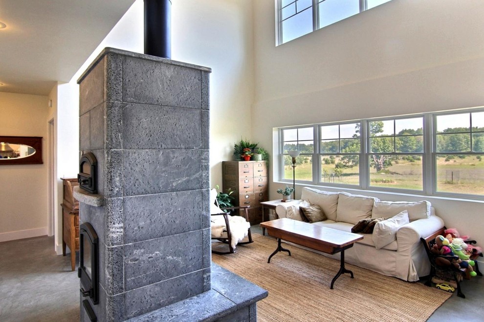 グランドラピッズにある中くらいなトラディショナルスタイルのおしゃれなリビング (白い壁、コンクリートの床、薪ストーブ、石材の暖炉まわり) の写真