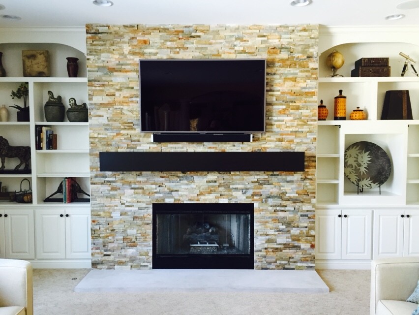 Cette image montre un grand salon traditionnel ouvert avec un mur blanc, moquette, une cheminée standard, un manteau de cheminée en pierre et un téléviseur fixé au mur.