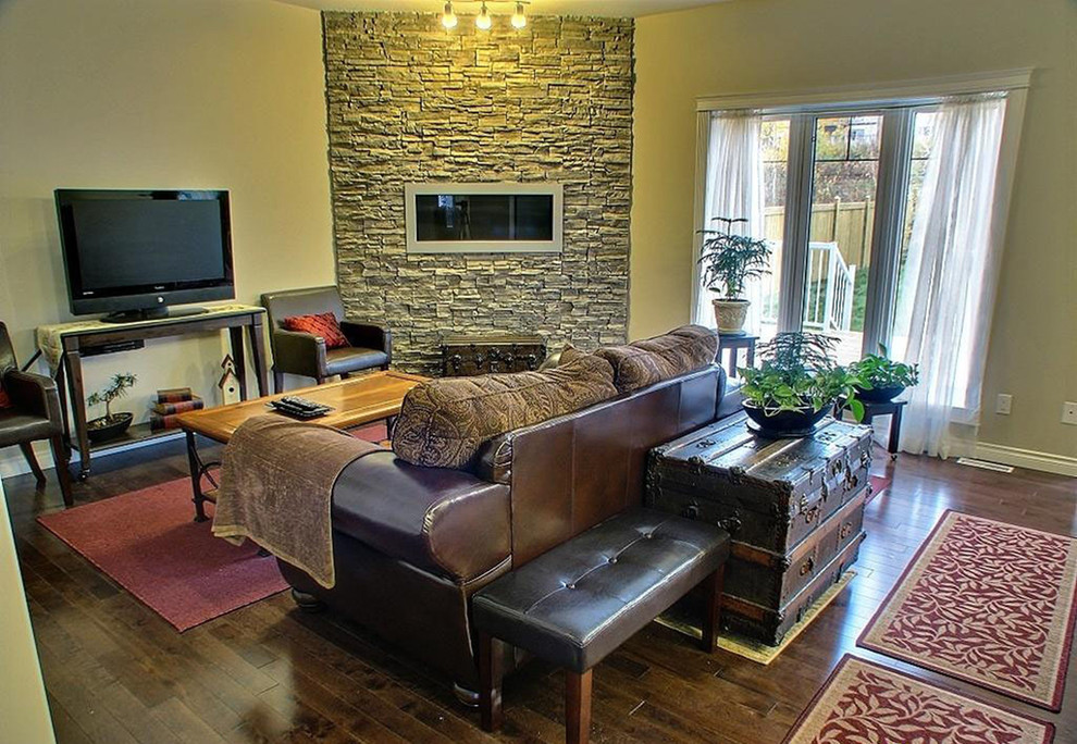 Mittelgroßes, Abgetrenntes Klassisches Wohnzimmer mit beiger Wandfarbe, dunklem Holzboden, Gaskamin, Kaminumrandung aus Stein, freistehendem TV und braunem Boden in San Diego