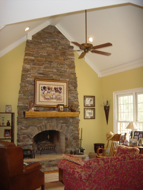 Diseño de salón abierto tradicional de tamaño medio con paredes amarillas y marco de chimenea de piedra