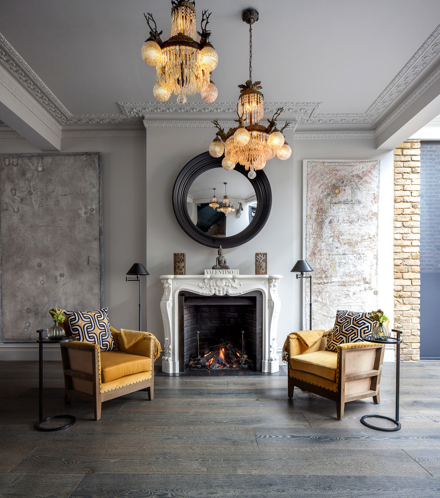 他の地域にある中くらいなトランジショナルスタイルのおしゃれなリビング (濃色無垢フローリング、標準型暖炉、グレーの床、白い壁、石材の暖炉まわり) の写真