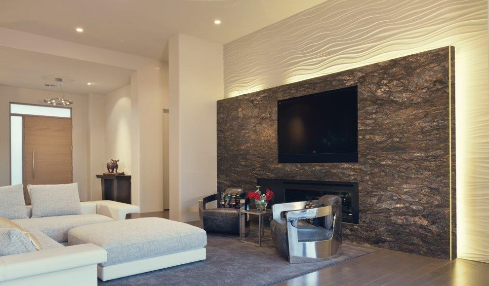 Großes, Offenes Modernes Wohnzimmer mit grauer Wandfarbe, braunem Holzboden, Gaskamin, Kaminumrandung aus Stein und TV-Wand in Phoenix