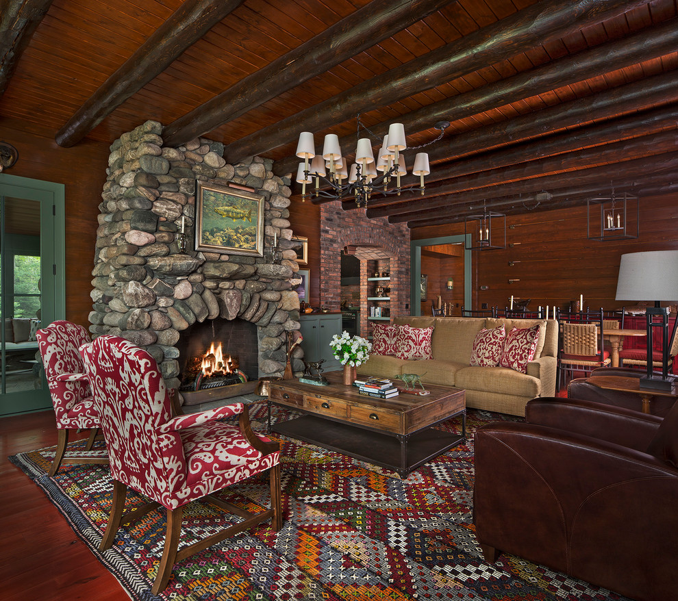 Ejemplo de salón abierto rural sin televisor con paredes marrones, suelo de madera en tonos medios, todas las chimeneas y marco de chimenea de piedra