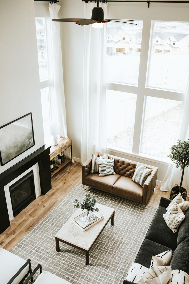 Immagine di un soggiorno moderno aperto con sala formale, pareti bianche, pavimento in laminato, stufa a legna, cornice del camino piastrellata e pavimento marrone