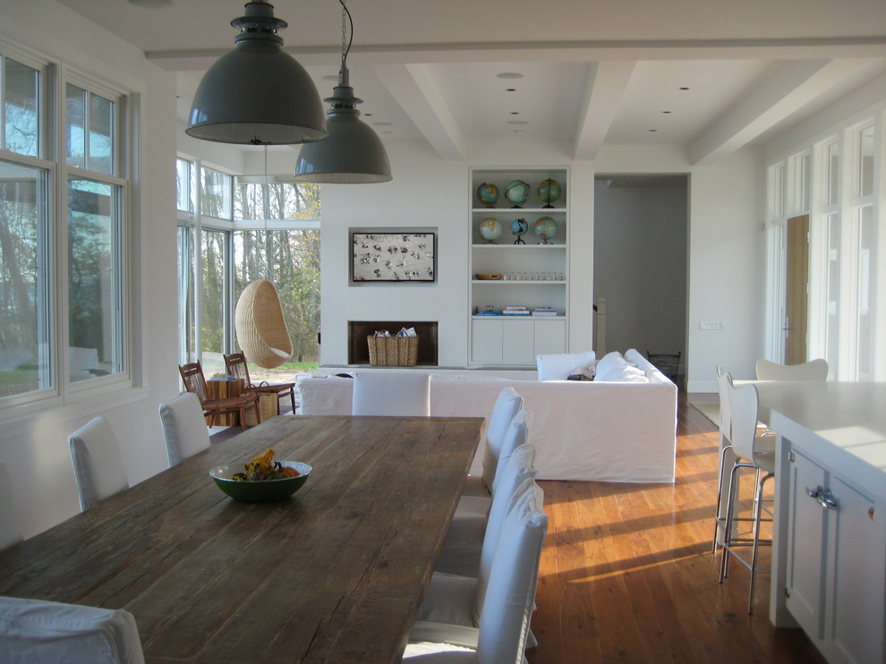 Inspiration for a coastal open concept medium tone wood floor and brown floor living room remodel in Milwaukee with white walls, a plaster fireplace and a concealed tv