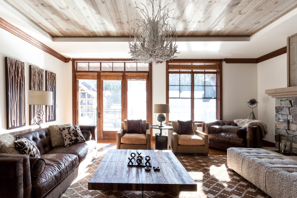 Foto de salón para visitas rústico sin televisor con paredes blancas, suelo de madera en tonos medios, marco de chimenea de piedra y alfombra