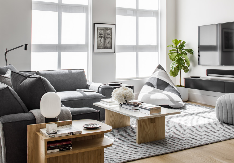 Foto di un soggiorno contemporaneo di medie dimensioni e aperto con libreria, pareti bianche, parquet chiaro e TV a parete