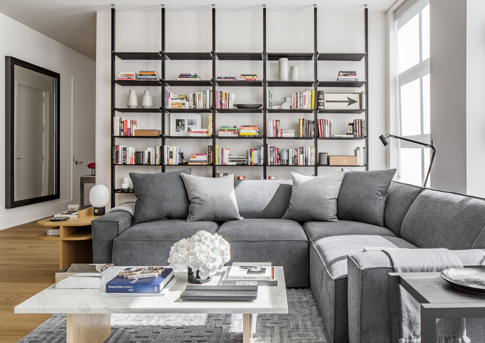 Foto di un soggiorno minimal di medie dimensioni e aperto con libreria, pareti bianche, parquet chiaro e TV a parete