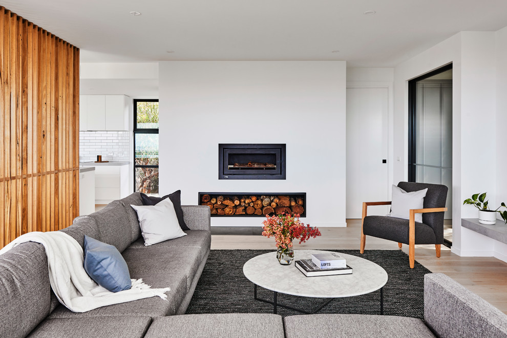 This is an example of a medium sized modern formal open plan living room in Other with white walls, light hardwood flooring, a ribbon fireplace, a plastered fireplace surround, a wall mounted tv and brown floors.