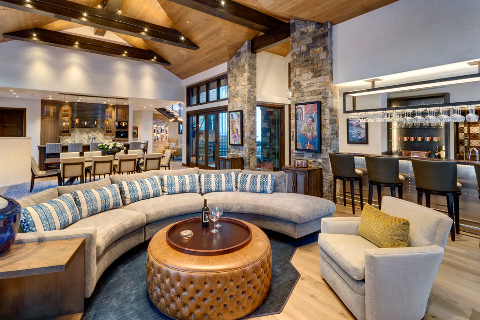 Expansive rustic open plan living room in Denver with a home bar, beige walls, a wall mounted tv and light hardwood flooring.