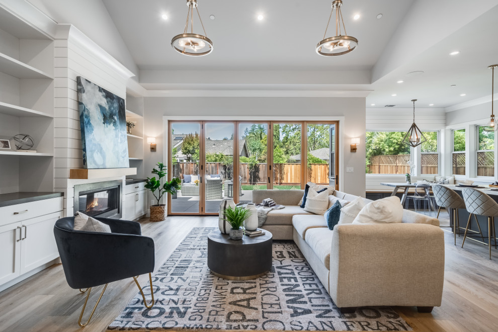 Large transitional open concept light wood floor, gray floor, vaulted ceiling and shiplap wall living room photo in San Francisco with gray walls, a ribbon fireplace, a stone fireplace and a wall-mounted tv