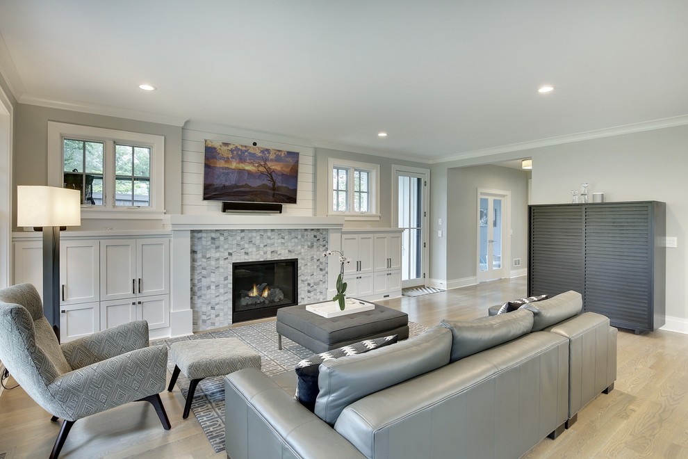 This is an example of a large traditional open plan living room in Minneapolis with grey walls, medium hardwood flooring, a standard fireplace, a tiled fireplace surround, a wall mounted tv and brown floors.