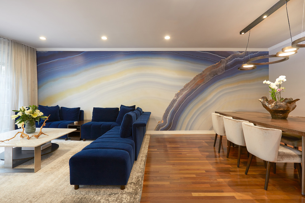 Mittelgroßes, Repräsentatives, Offenes Modernes Wohnzimmer mit blauer Wandfarbe, hellem Holzboden, Eckkamin, Kaminumrandung aus Stein, TV-Wand und buntem Boden in Los Angeles