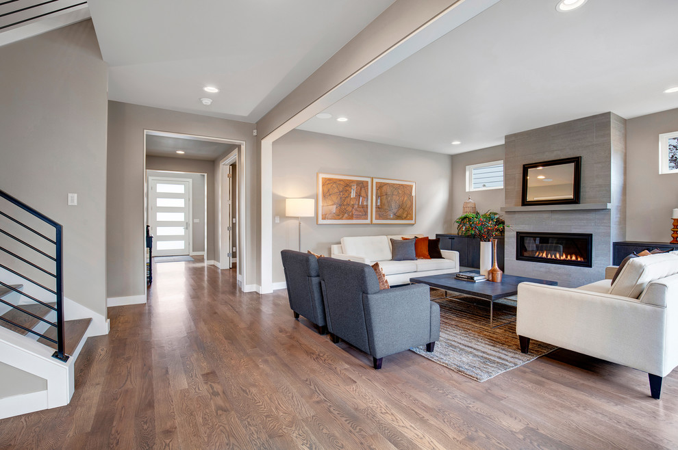 Example of a trendy open concept medium tone wood floor living room design in Seattle with a standard fireplace, a tile fireplace and a wall-mounted tv