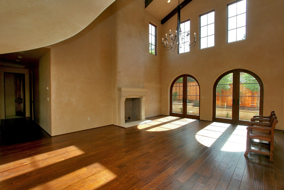 Exemple d'un grand salon méditerranéen ouvert avec un mur beige, parquet foncé, une cheminée standard, un manteau de cheminée en plâtre et un sol beige.