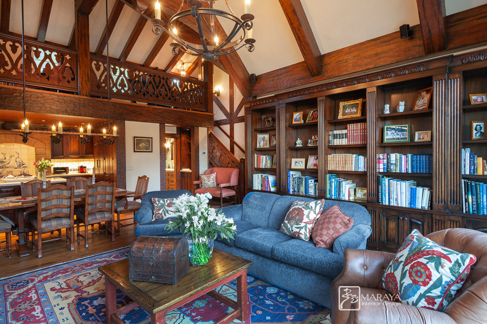 Bild på ett mellanstort lantligt loftrum, med ett bibliotek, beige väggar, mellanmörkt trägolv, en standard öppen spis, en spiselkrans i sten, en dold TV och brunt golv