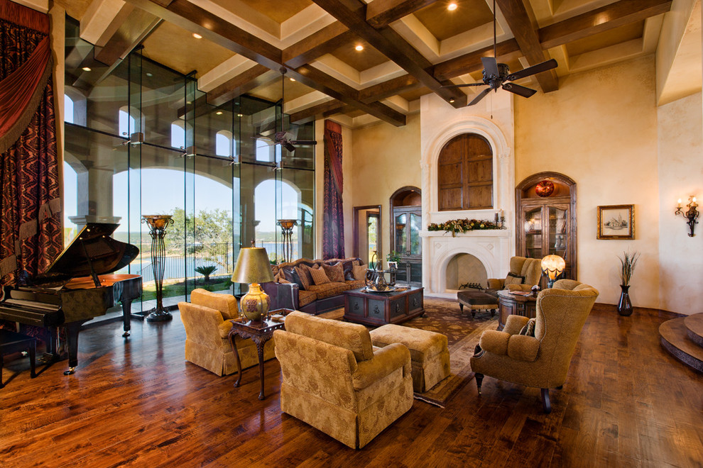 Photo of an expansive mediterranean formal open plan living room in Austin with beige walls, medium hardwood flooring, a standard fireplace, a stone fireplace surround, a concealed tv and brown floors.