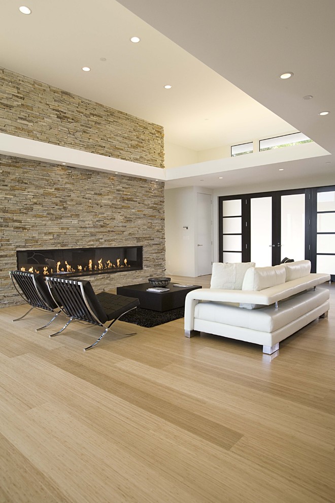 Offenes Modernes Wohnzimmer mit Gaskamin, Kaminumrandung aus Stein, weißer Wandfarbe und Bambusparkett in San Francisco
