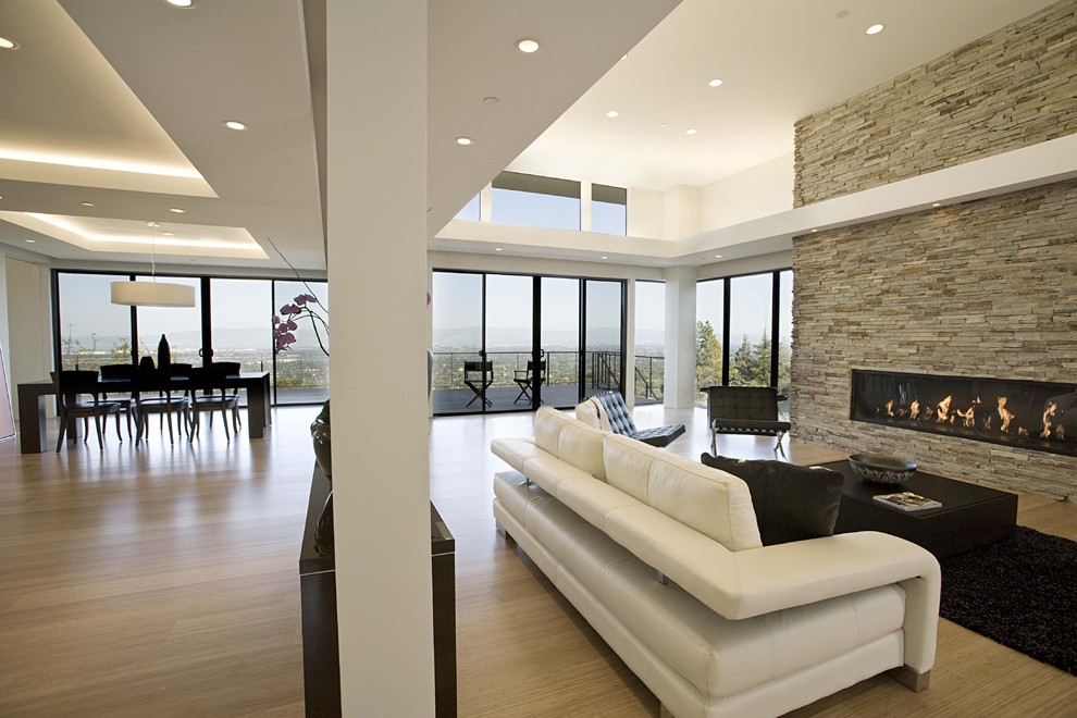 Стильный дизайн: гостиная комната в современном стиле с полом из бамбука, горизонтальным камином и фасадом камина из камня - последний тренд