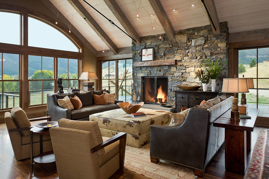 Exemple d'un grand salon montagne ouvert avec un mur vert, parquet foncé, une cheminée standard, un manteau de cheminée en pierre, un téléviseur dissimulé et un sol marron.