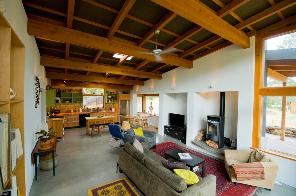 Immagine di un piccolo soggiorno contemporaneo aperto con pareti bianche, pavimento in cemento, stufa a legna e TV autoportante