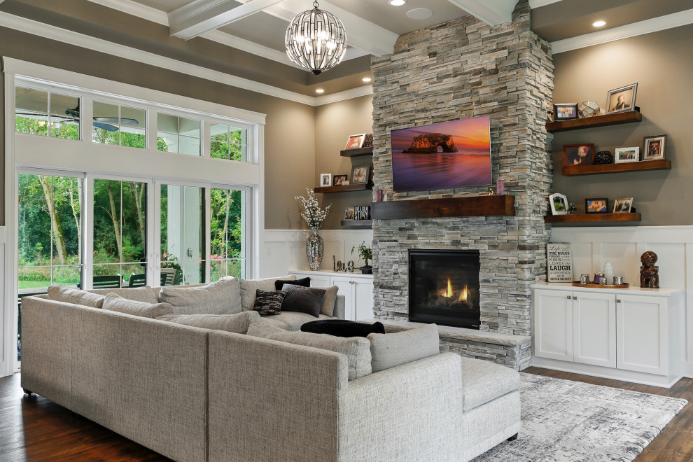 Mid-sized cottage open concept dark wood floor, brown floor, coffered ceiling and wainscoting living room photo in New York with beige walls, a standard fireplace, a wall-mounted tv and a stacked stone fireplace