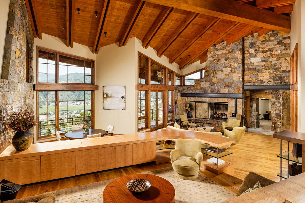 Modern open plan living room in Denver with light hardwood flooring, a stone fireplace surround and a concealed tv.