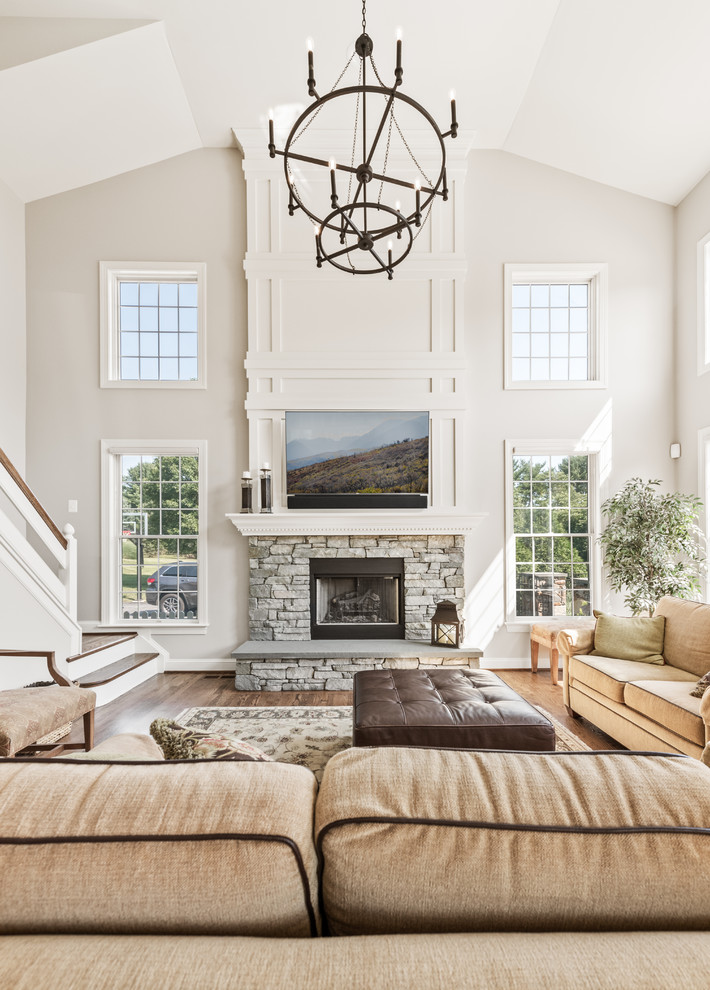 Photo of a large traditional enclosed living room in Philadelphia with white walls, medium hardwood flooring, a standard fireplace, a stone fireplace surround, a wall mounted tv and brown floors.