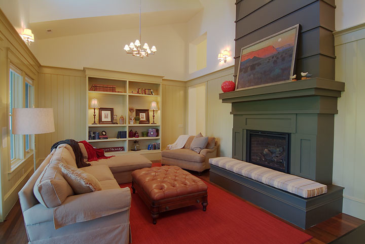 Aménagement d'un salon mansardé ou avec mezzanine classique de taille moyenne avec un mur beige, un sol en bois brun, une cheminée standard et un manteau de cheminée en plâtre.