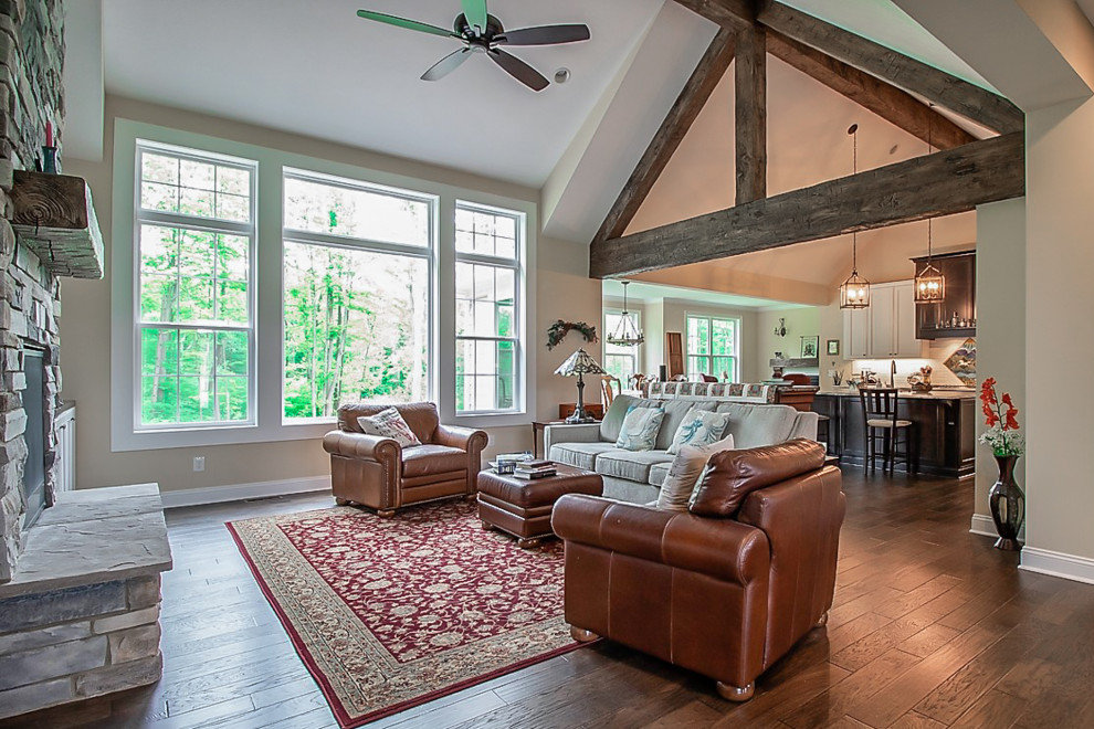 Design ideas for an expansive traditional open plan living room in Cleveland with beige walls, medium hardwood flooring, a standard fireplace, a stone fireplace surround, brown floors and exposed beams.