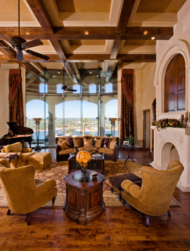 Inspiration for an expansive mediterranean open plan living room in Austin with beige walls, medium hardwood flooring, a standard fireplace, a stone fireplace surround and a concealed tv.