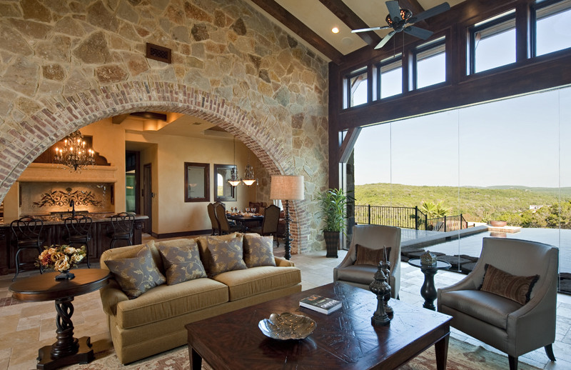 This is an example of an expansive rustic formal open plan living room in Austin with beige walls, travertine flooring, a standard fireplace, a stone fireplace surround and a concealed tv.
