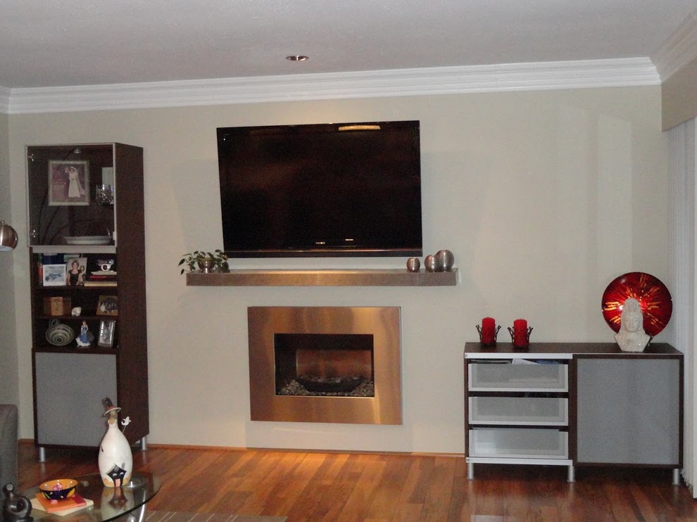 На фото: открытая гостиная комната среднего размера в современном стиле с бежевыми стенами, паркетным полом среднего тона, стандартным камином, фасадом камина из металла и телевизором на стене