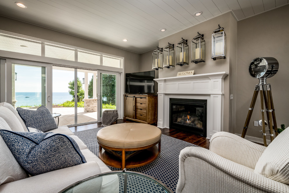 Cette image montre un salon design avec un mur beige, un sol en bois brun, une cheminée standard, un manteau de cheminée en plâtre et un téléviseur indépendant.