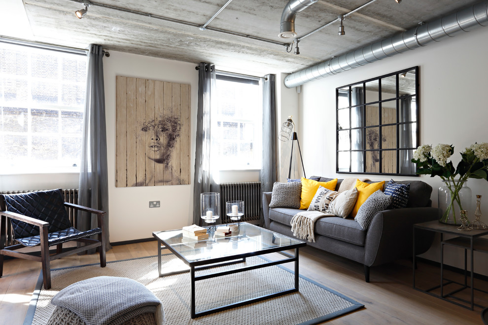 Mittelgroßes, Fernseherloses, Abgetrenntes Industrial Wohnzimmer ohne Kamin mit braunem Holzboden und weißer Wandfarbe in London