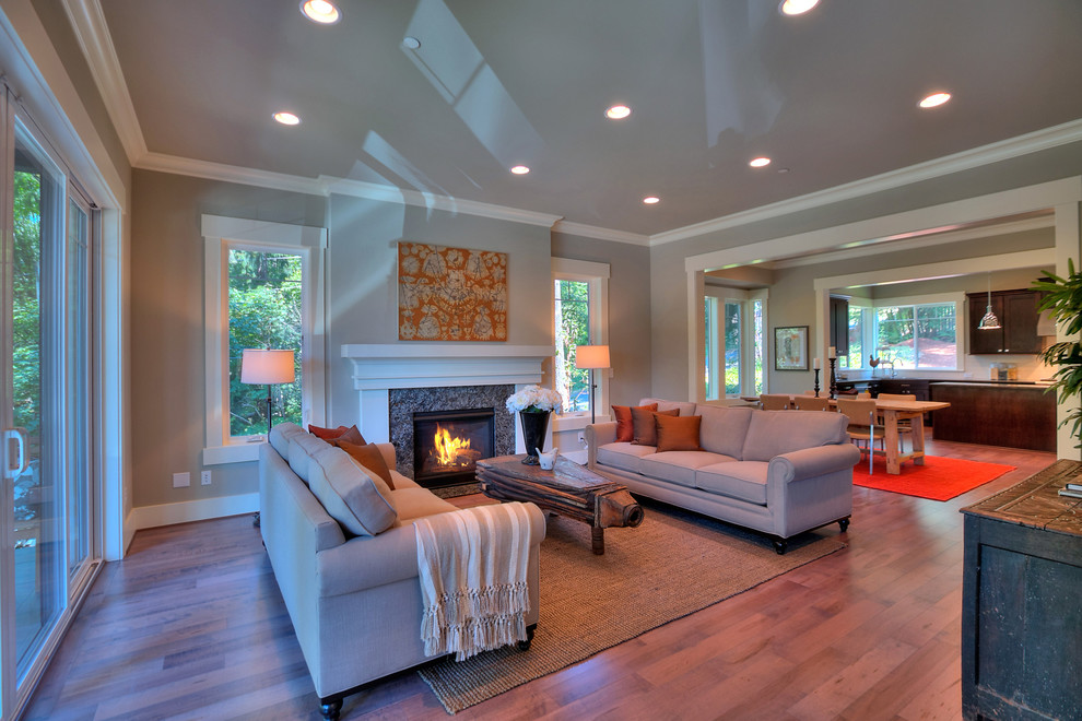 Photo of a medium sized classic formal open plan living room in Seattle with grey walls, medium hardwood flooring, a standard fireplace, a stone fireplace surround and a wall mounted tv.