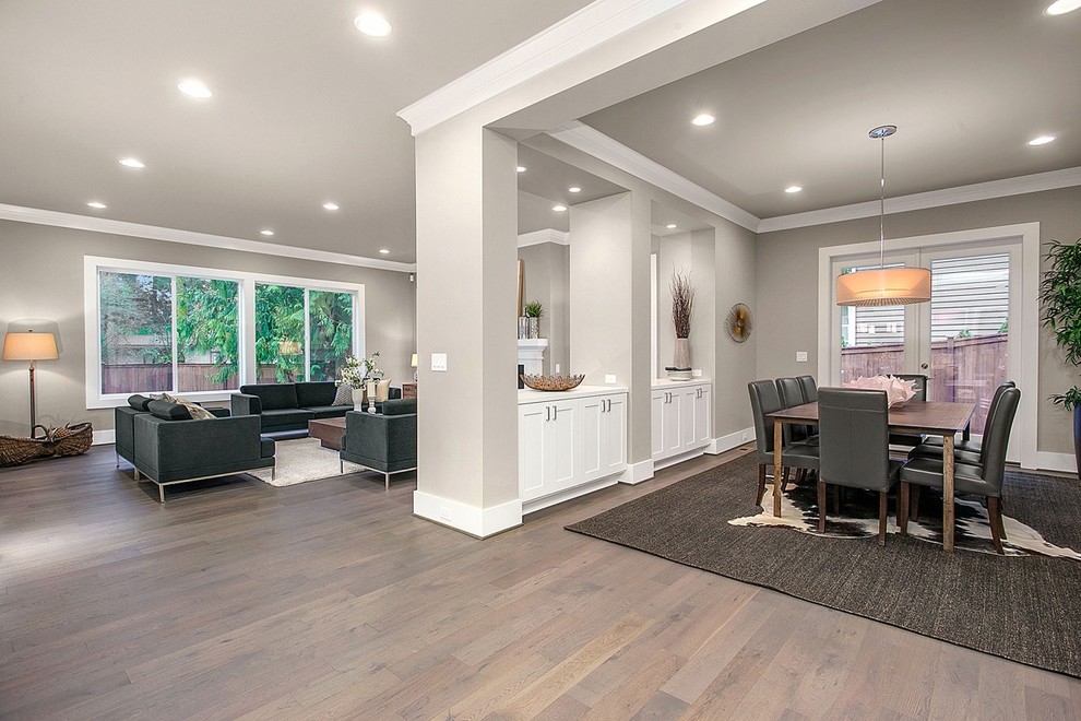 Diseño de salón abierto de estilo americano grande con paredes grises y suelo de madera en tonos medios