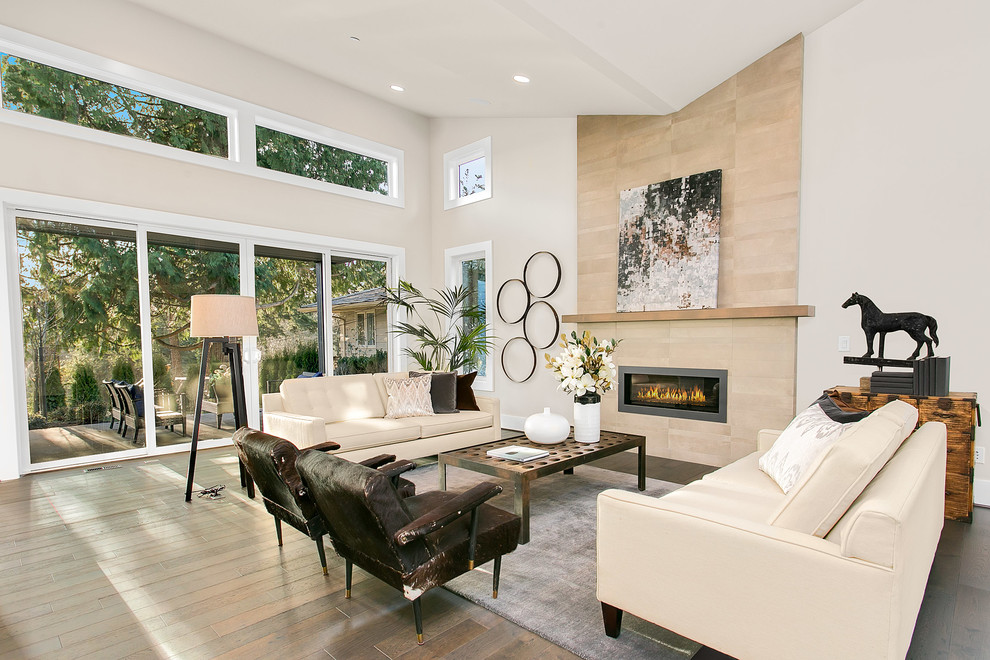 Photo of a large modern open plan living room in Seattle with grey walls, medium hardwood flooring, a standard fireplace and a tiled fireplace surround.