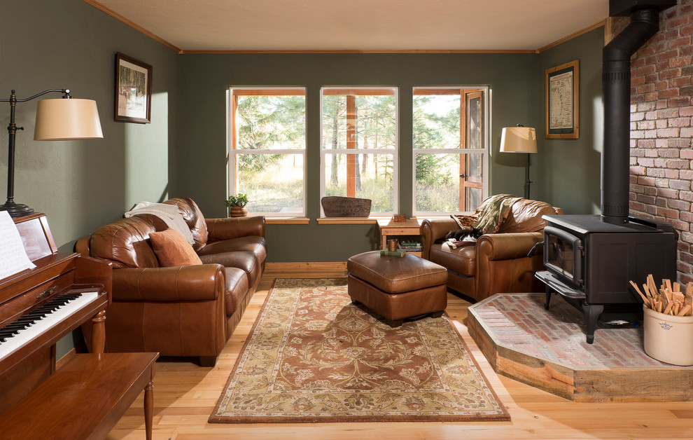 Foto de salón abierto rural pequeño con paredes verdes, suelo de madera clara, estufa de leña y marco de chimenea de ladrillo