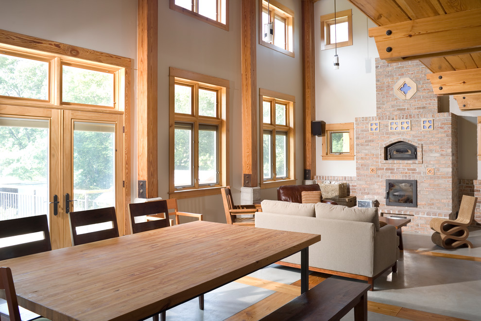 Cette photo montre un salon montagne de taille moyenne et ouvert avec un mur beige, sol en béton ciré, un poêle à bois, un manteau de cheminée en brique et aucun téléviseur.