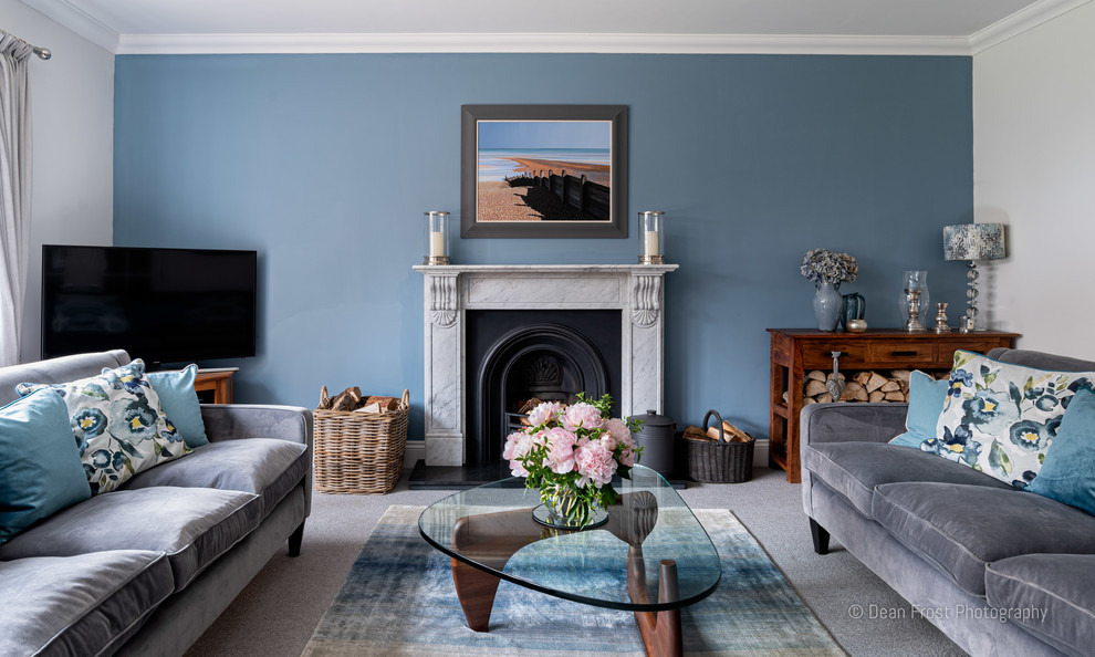 他の地域にある中くらいなモダンスタイルのおしゃれなリビング (青い壁、カーペット敷き、標準型暖炉、石材の暖炉まわり、据え置き型テレビ、グレーの床) の写真
