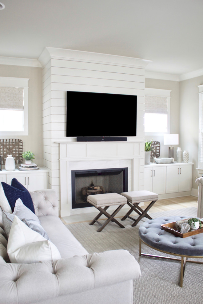 Modern inredning av ett stort allrum med öppen planlösning, med beige väggar, ljust trägolv, en standard öppen spis, en väggmonterad TV och beiget golv